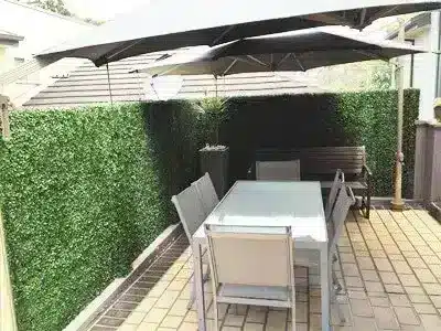 Artificial boxed hedging in a backyard dining setting with table