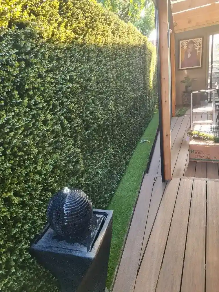 adding faux greenery on top of wooden fence